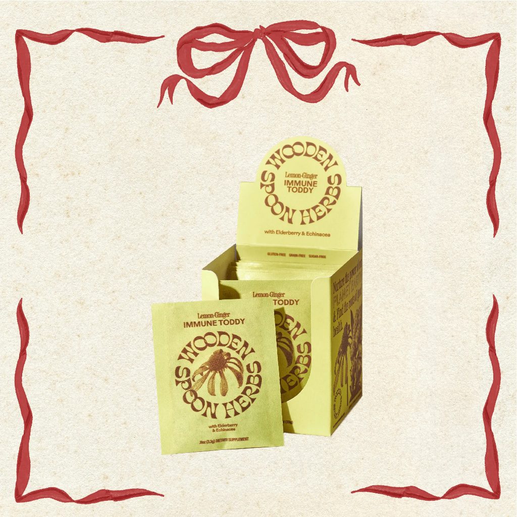 Boxes of Wooden Spoon Herbs Immune Toddy on a decorative background with red ribbons.