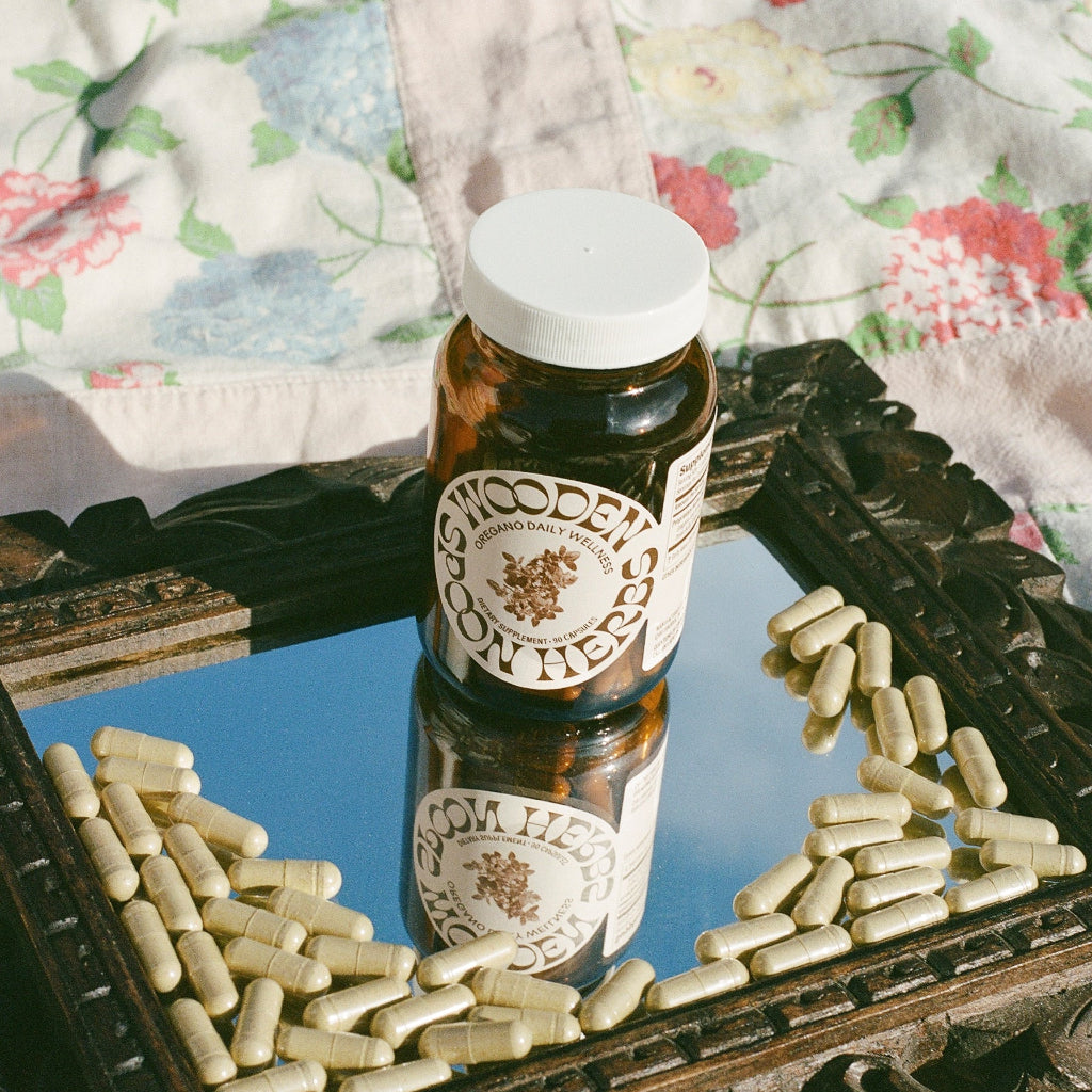 Bottle of 'Wooden Spoon Herb' on a decorative surface with scattered capsules.