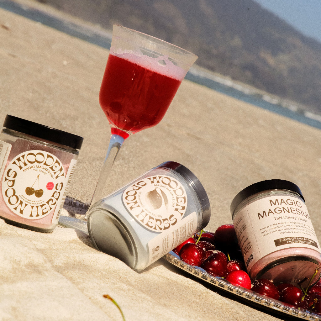 Magic Mag in Tart Cherry on a beach with cherries and a cocktail.