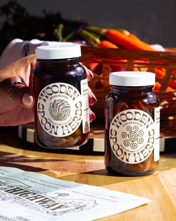 Two jars of 'Wooden Spoon' brand on a wooden table with vegetables in the background